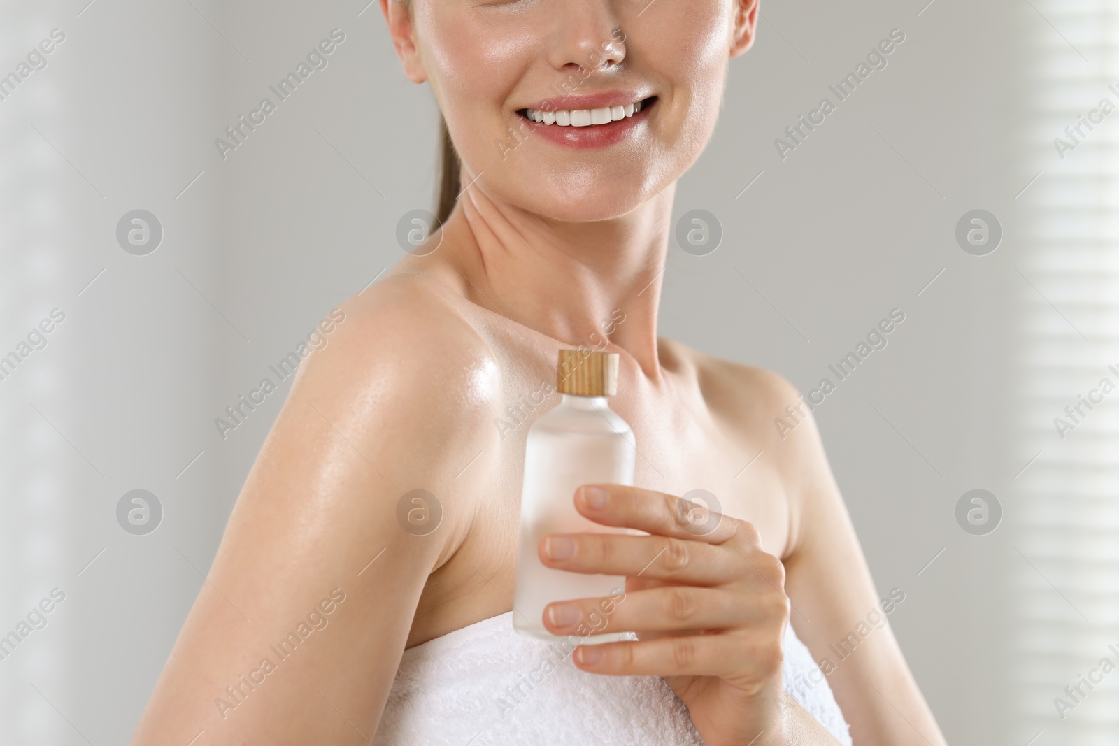 Photo of Woman with bottle of body oil indoors, closeup