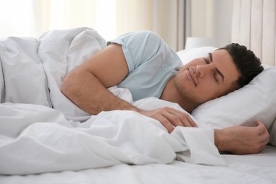 Man sleeping in bed with white linens at home