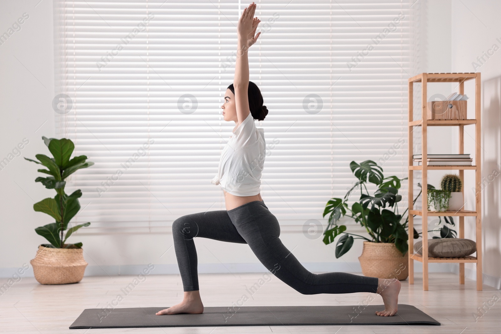 Photo of Girl practicing crescent asana on mat in yoga studio. High lunge pose