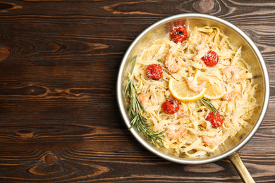 Photo of Delicious pasta with shrimps on wooden table, top view. Space for text