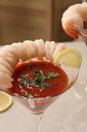 Photo of Tasty shrimp cocktail with sauce in glasses on white table, closeup