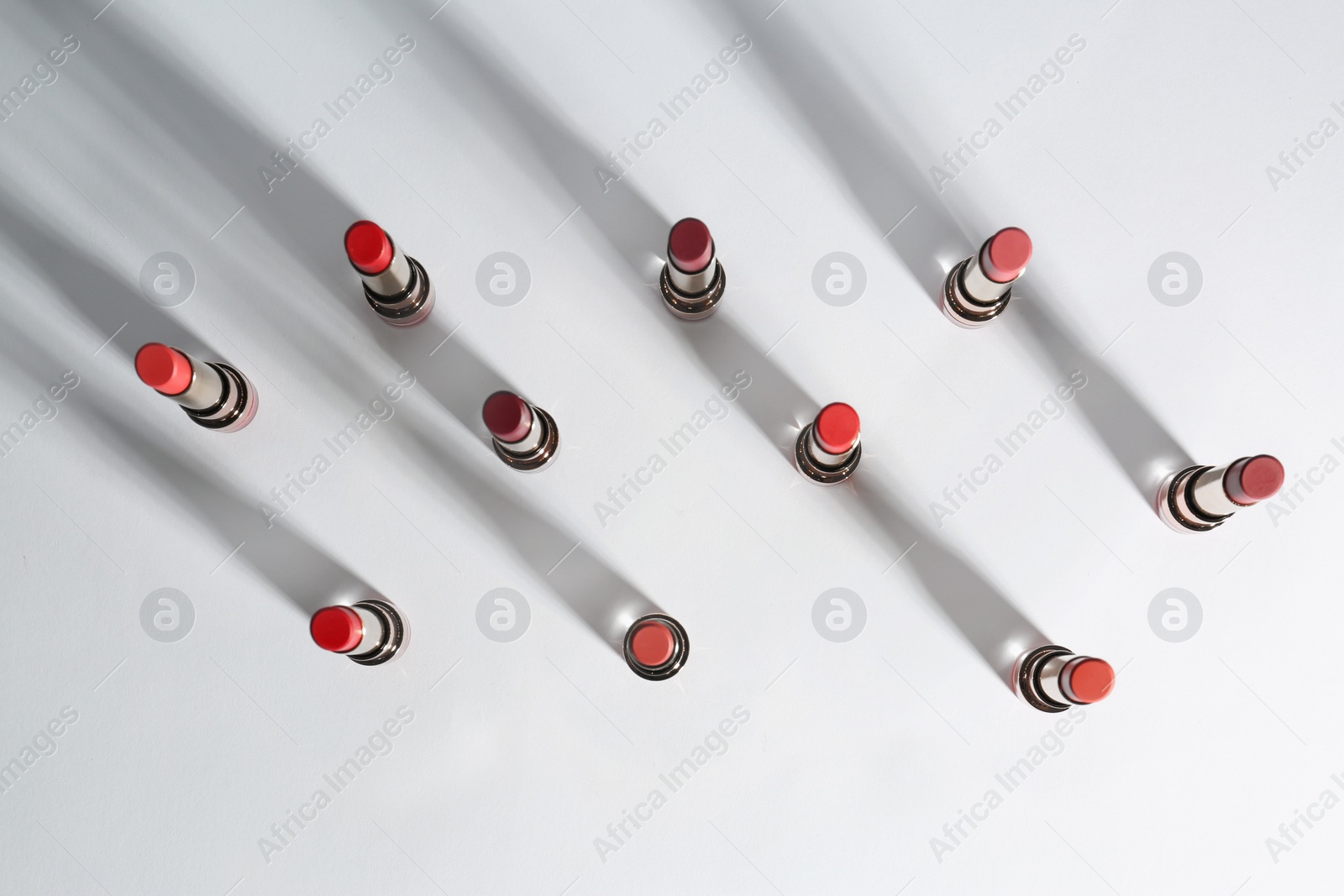 Photo of Set of bright lipsticks on white background, flat lay