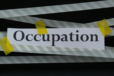 Word Occupation attached with yellow adhesive tape on black background