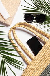 Flat lay composition with wicker bag, palm leaves and other beach accessories on white background