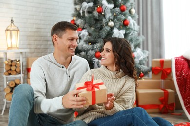 Image of Man presenting Christmas gift to his girlfriend at home 