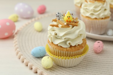 Tasty Easter cupcakes with vanilla cream and candies on table, closeup