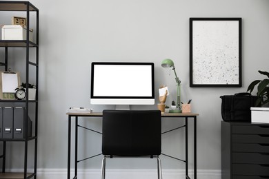 Photo of Comfortable office chair near desk with modern computer indoors