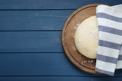 Photo of Fresh yeast dough with flour on blue wooden table, top view. Space for text