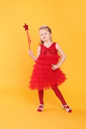 Photo of Cute girl in red dress with diadem and magic wand on yellow background. Little princess
