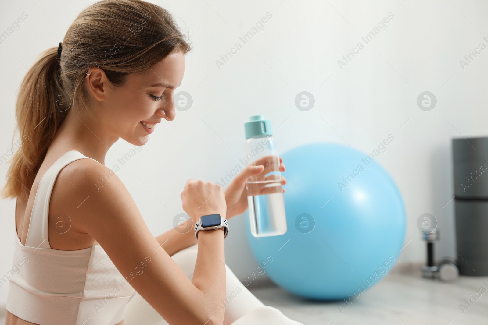 Photo of Young woman wearing smart watch during training indoors, space for text