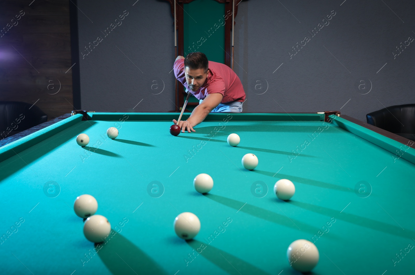 Photo of Handsome young man playing Russian billiard indoors