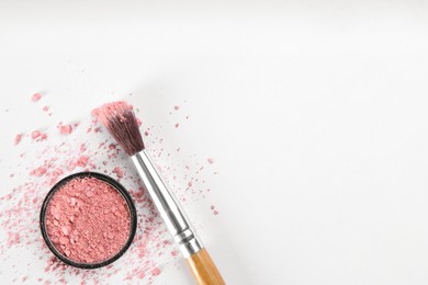 Makeup brush and scattered blush on white background, top view. Space for text
