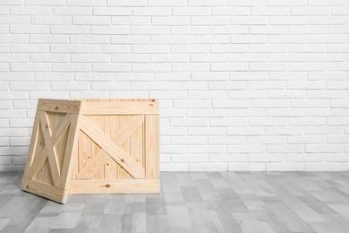 Photo of Wooden crate on floor at white brick wall. Space for text