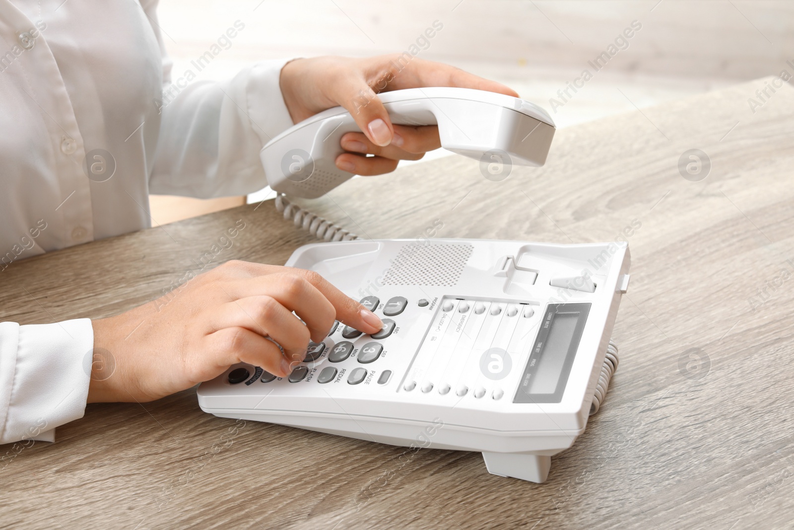 Photo of Woman dialing number on telephone at table indoors, closeup