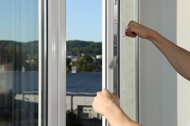 Photo of Worker installing plastic window indoors, closeup view