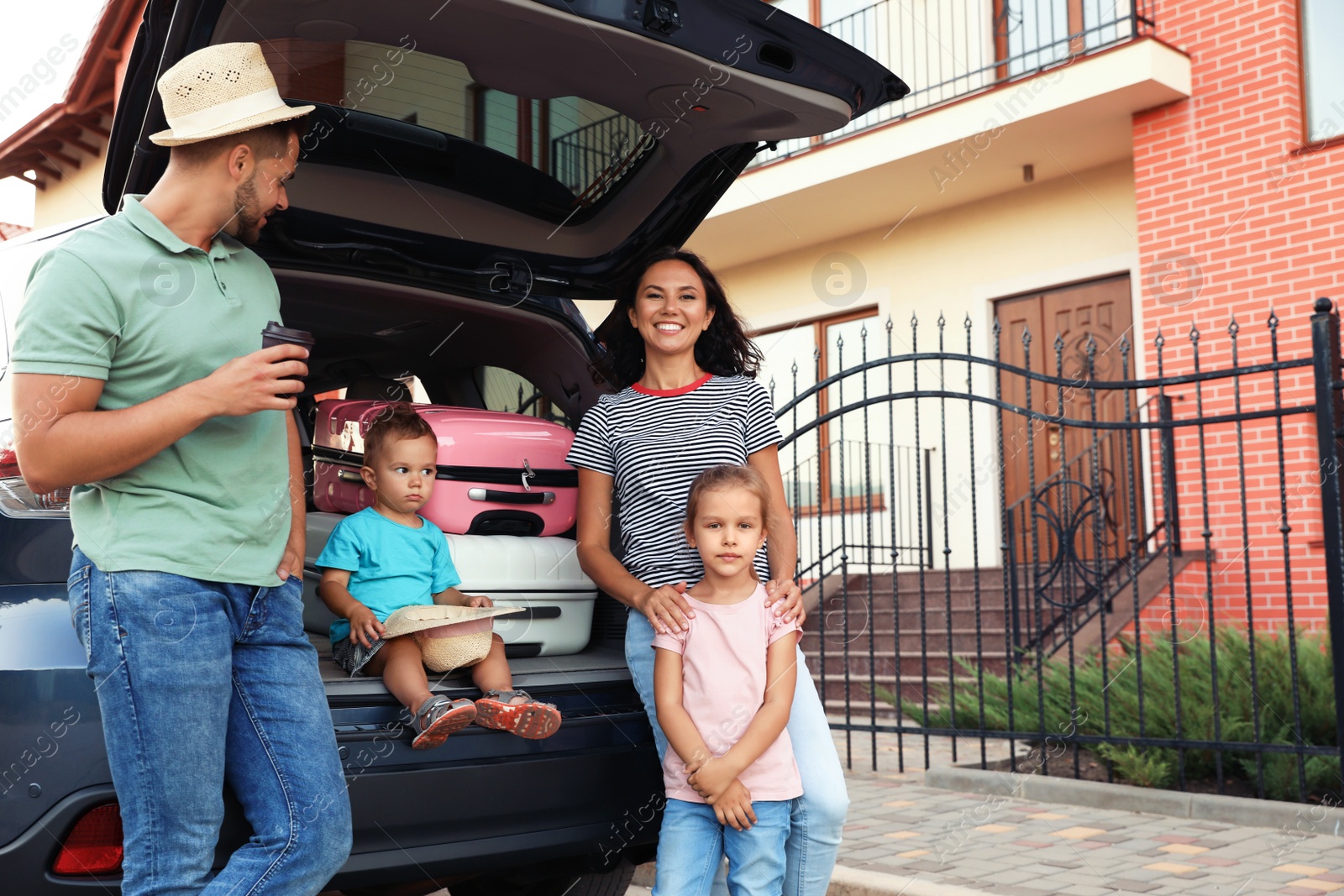 Photo of Happy family with suitcases near car in city street