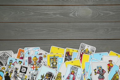 Photo of Tarot cards on grey wooden table, top view. Space for text
