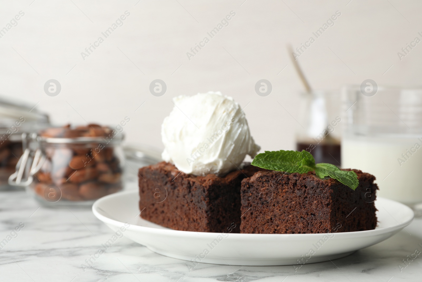 Photo of Plate with fresh brownies and ice-cream on table. Delicious chocolate pie