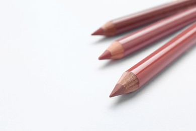 Photo of Different lip pencils on white background, closeup. Cosmetic product