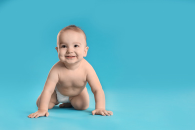 Cute little baby in diaper on light blue background. Space for text