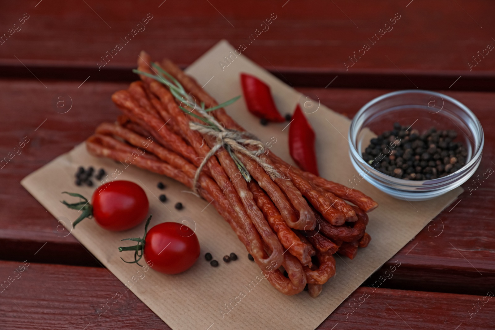 Photo of Tasty dry cured sausages (kabanosy) and ingredients on wooden table