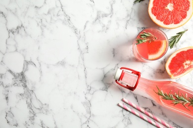 Flat lay composition with grapefruits, glass of cocktail and bottle on marble background. Space for text