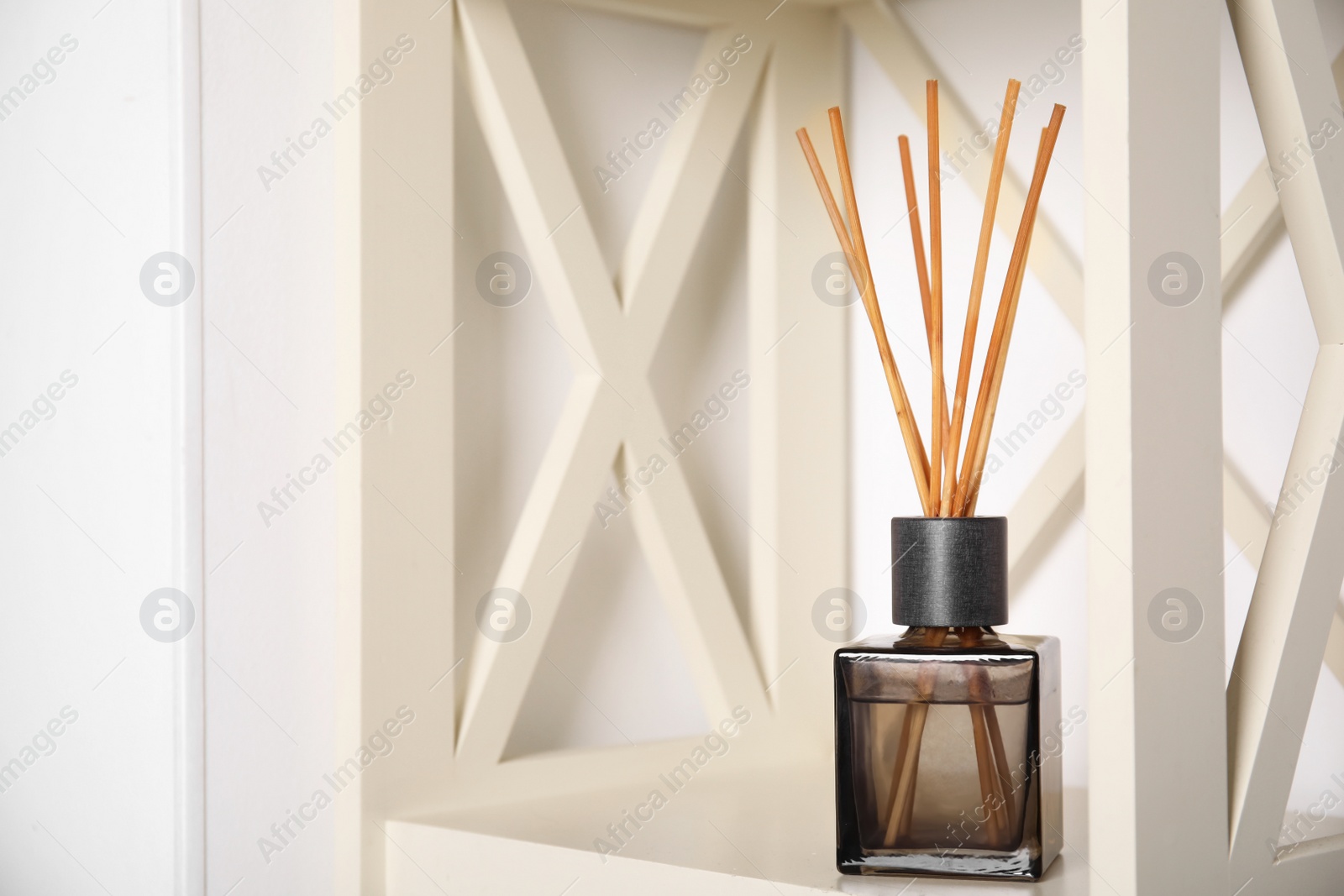 Photo of Aromatic reed freshener on wooden shelf indoors, space for text