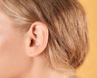 Photo of Young woman on color background, closeup. Hearing problem