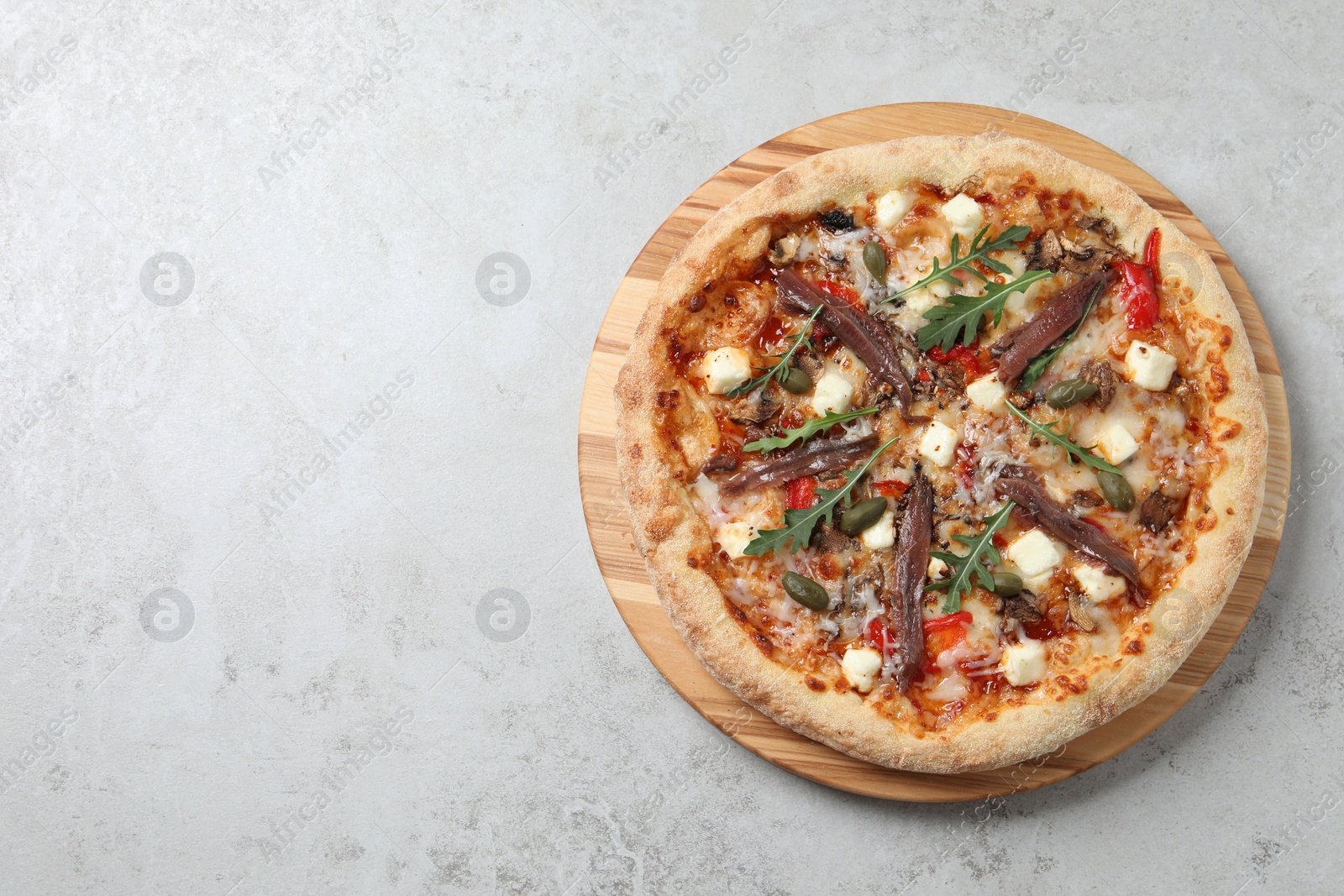 Photo of Tasty pizza with anchovies, arugula and olives on grey table, top view. Space for text