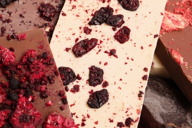 Photo of Different chocolate bars with freeze dried fruits as background, closeup