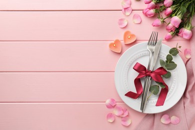 Photo of Place setting with heart shaped candles and bouquet of roses for romantic dinner on pink wooden table, flat lay. Space for text