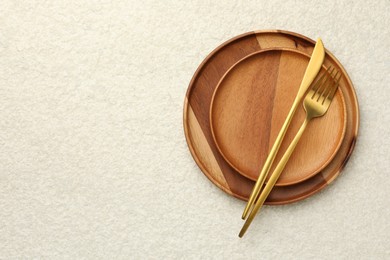 Photo of Stylish setting with cutlery and plates on light textured table, top view. Space for text