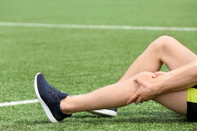 Photo of Man in sportswear suffering from knee pain at soccer field, closeup