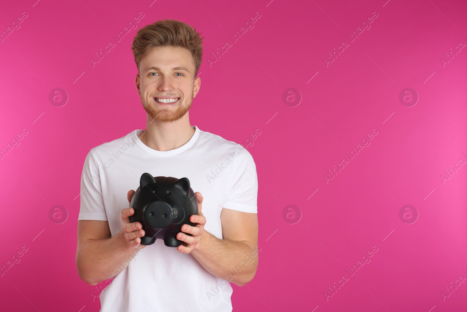 Photo of Young man with piggy bank on color background, space for text. Money saving