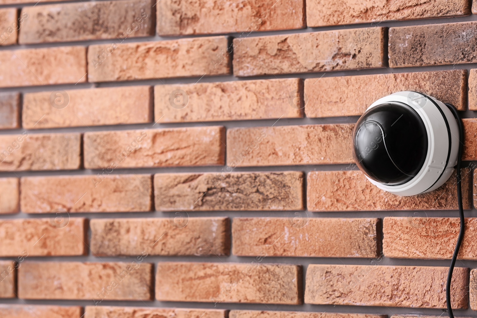 Photo of Modern security CCTV camera on brick wall