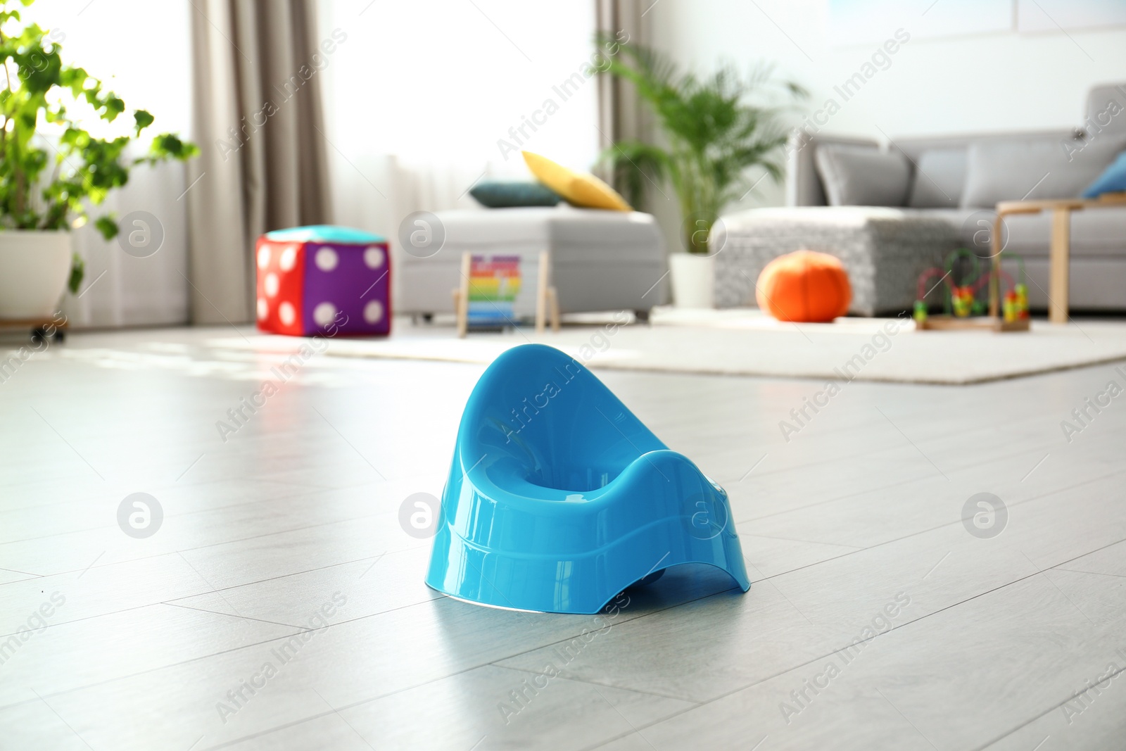 Photo of Modern blue potty on floor in nursery room. Toilet training