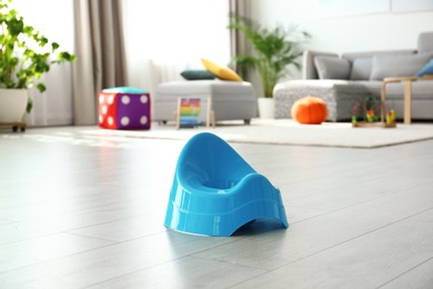 Photo of Modern blue potty on floor in nursery room. Toilet training