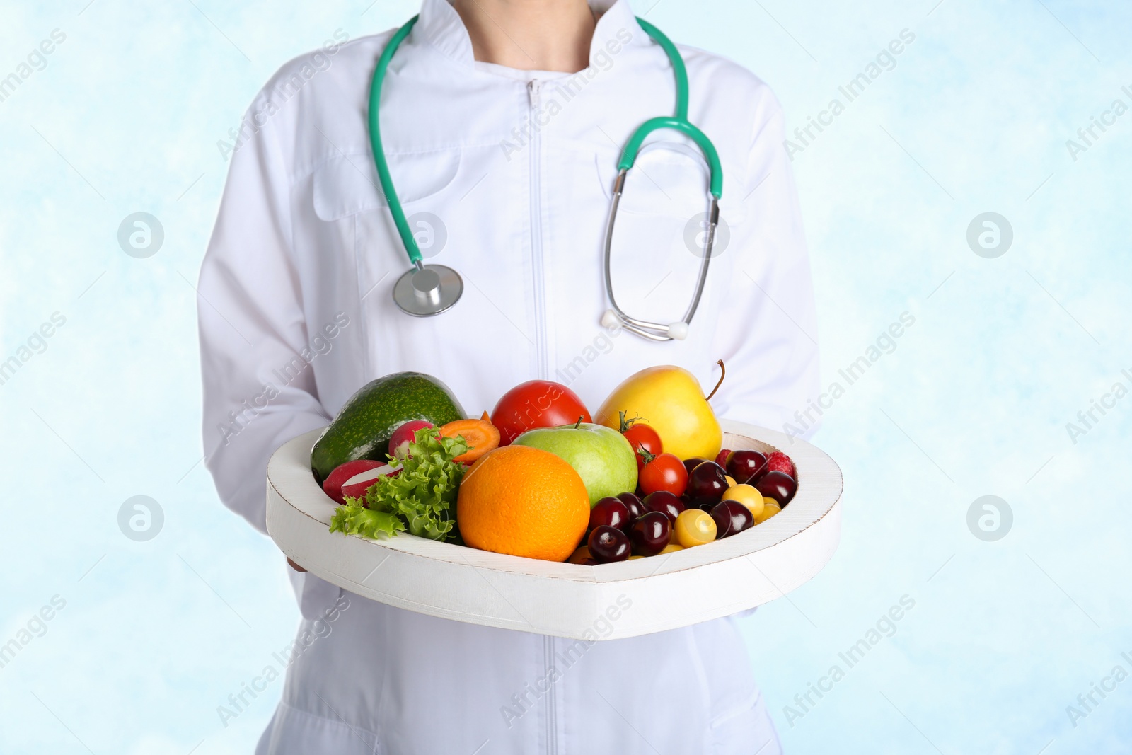 Photo of Female doctor with fresh products on light background. Cardiac diet