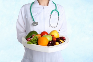 Photo of Female doctor with fresh products on light background. Cardiac diet