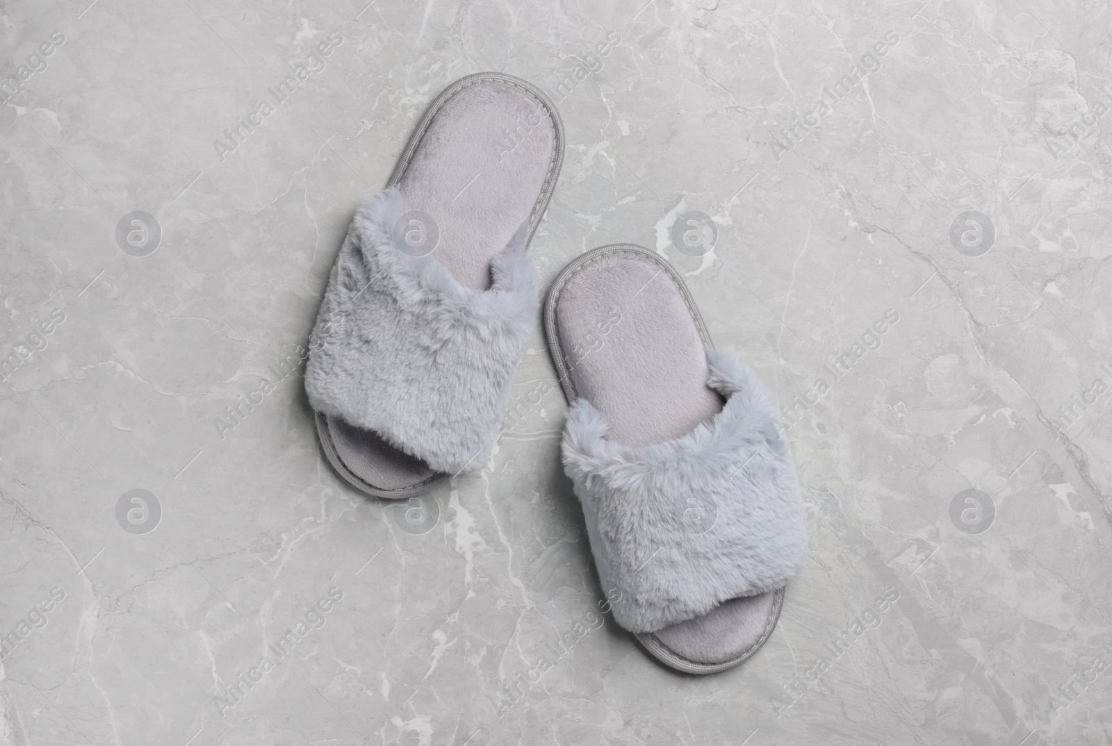 Photo of Pair of soft slippers on grey marble floor, top view