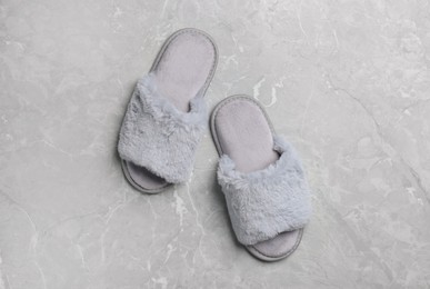 Photo of Pair of soft slippers on grey marble floor, top view