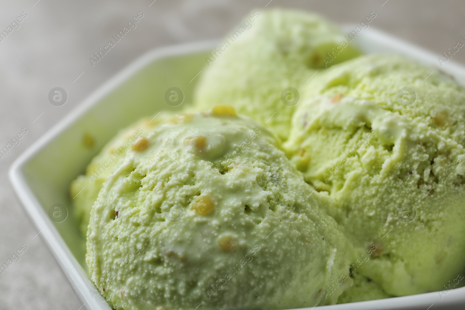 Photo of Delicious pistachio ice cream in bowl, closeup