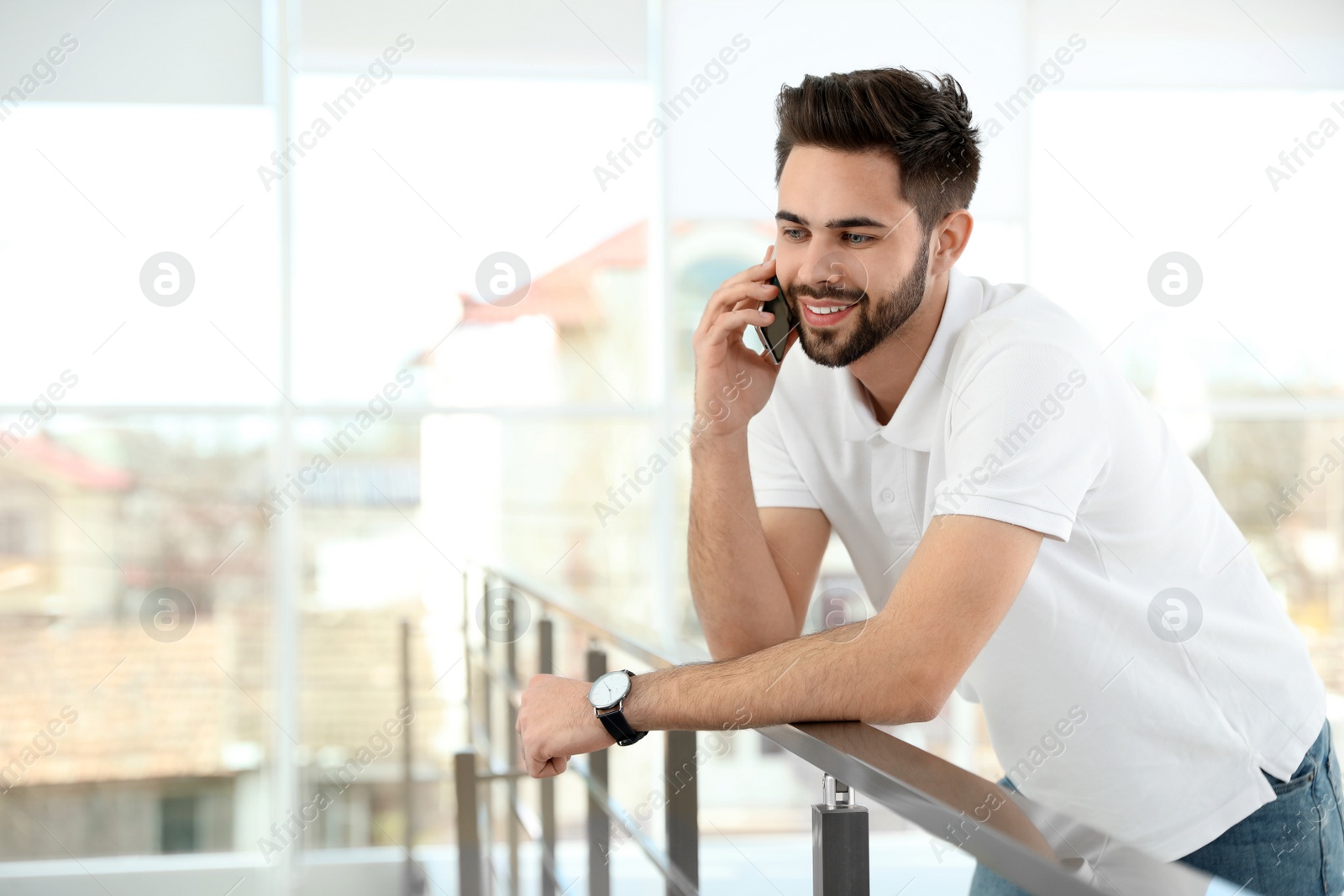 Photo of Portrait of handsome man talking on phone in light room