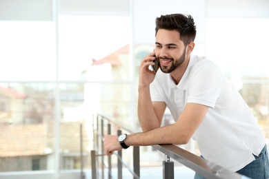 Portrait of handsome man talking on phone in light room