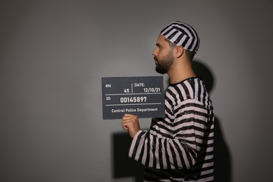 Photo of Prisoner in special uniform with mugshot letter board 
on grey background