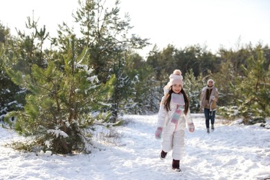 Photo of Cute little girl with her parents outdoors on winter day. Christmas vacation