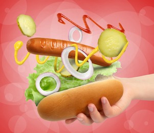 Image of Woman making hot dog on red background, closeup. Ingredients levitating over bun