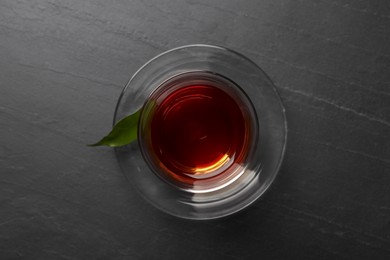 Photo of Glass with traditional Turkish tea on black table, top view