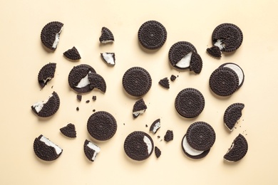 Photo of Tasty chocolate cookies with cream on color background, flat lay
