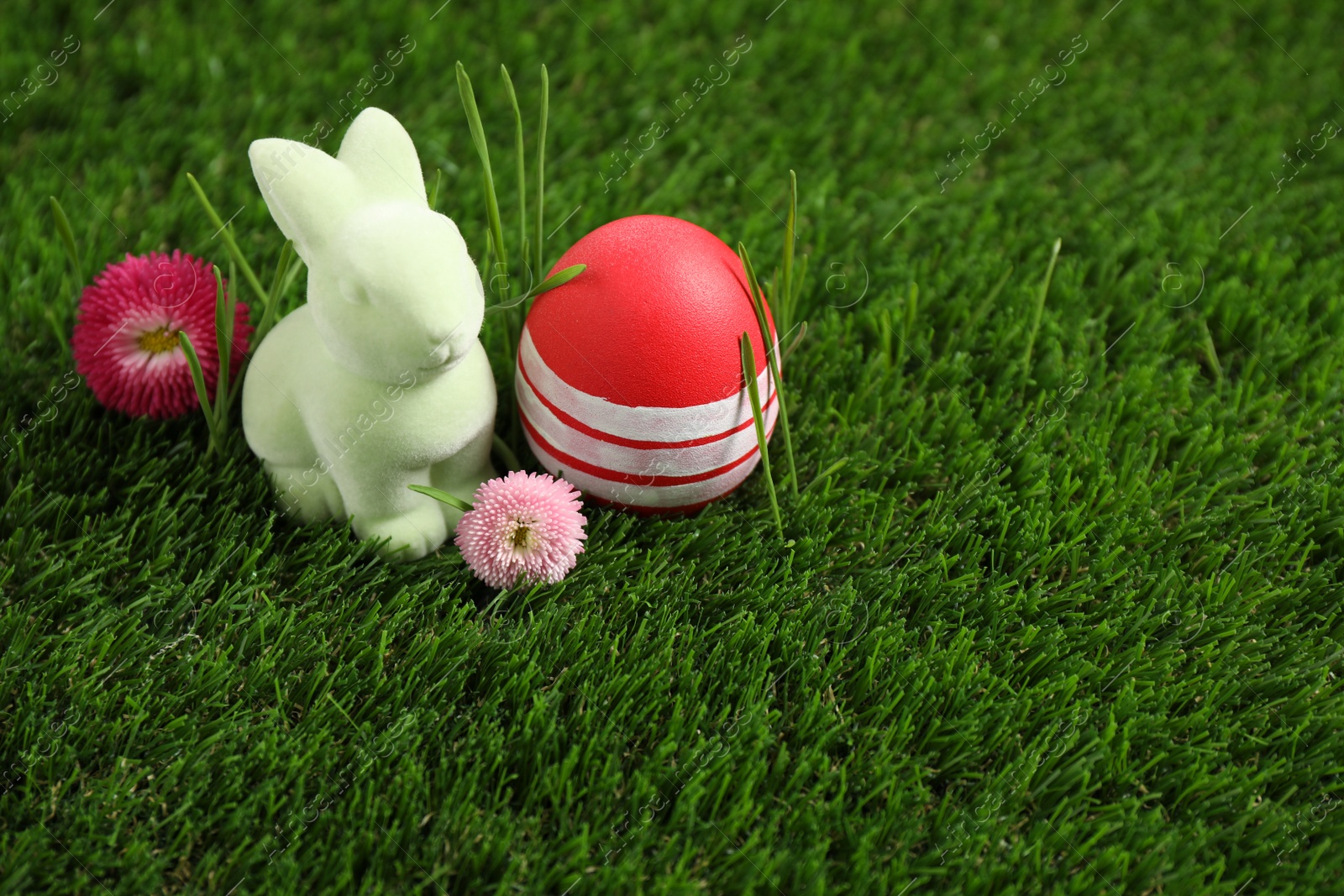 Photo of Colorful Easter egg, rabbit and daisy flowers on green grass. Space for text